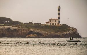 Triathlon Portocolom nageant avec le phare en arrière-plan