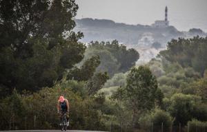 Segmento ciclistico con il faro di Porto Colom sullo sfondo
