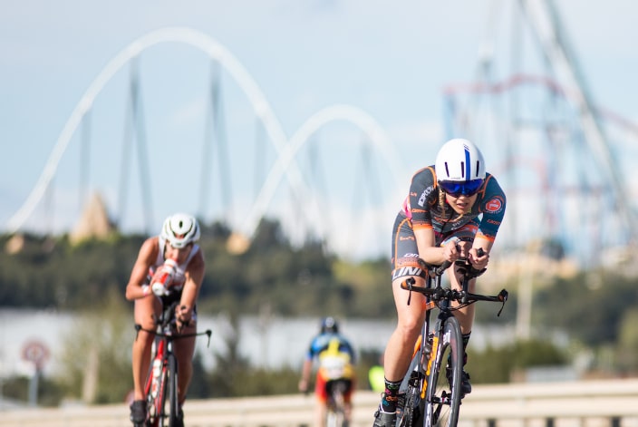 image of two triathletes with PortAventura in the background