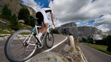 Canva/ Ein Radfahrer, der einen Bergpass hinauffährt