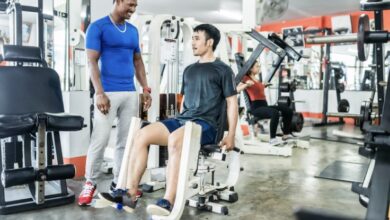 Canva: A personal trainer and his student on the adductor and adductor machine