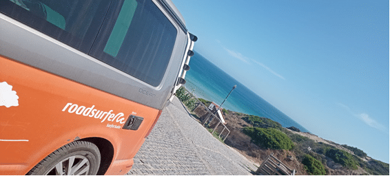 Bild eines Roadsurfers mit einer Bucht im Hintergrund in Portugal