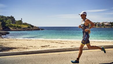 Un triatleta che corre a Porto Colom con il faro sullo sfondo