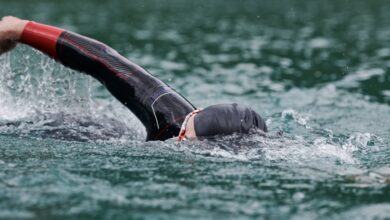 Canva/ ein Triathlet, der im offenen Wasser schwimmt