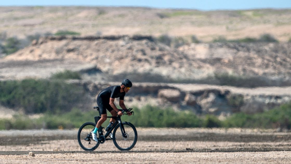 Triatleta compitiendo en el segmento ciclista del Challenge Sir Bani Yas 2026 en un entorno desértico