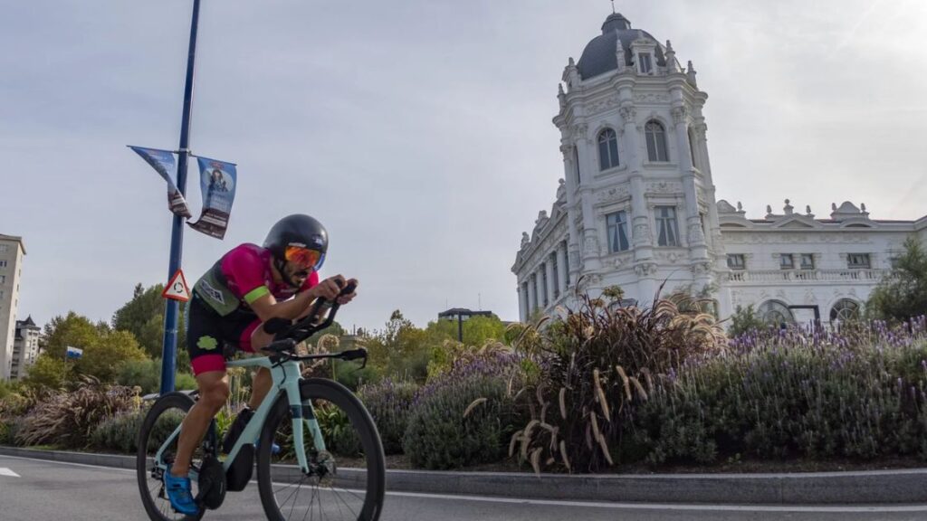 Triatleta compitiendo en el segmento ciclista del Triatlón Ciudad de Santander junto al edificio del Banco Santander