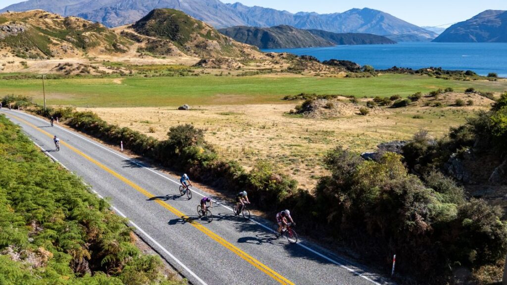 Ciclistas compitiendo en el segmento de ciclismo del Challenge Wānaka junto al lago Wānaka en Nueva Zelanda