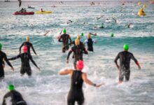 Triatleti che entrano in acqua alla partenza di un IRONMAN secondo il regolamento IRONMAN 2026