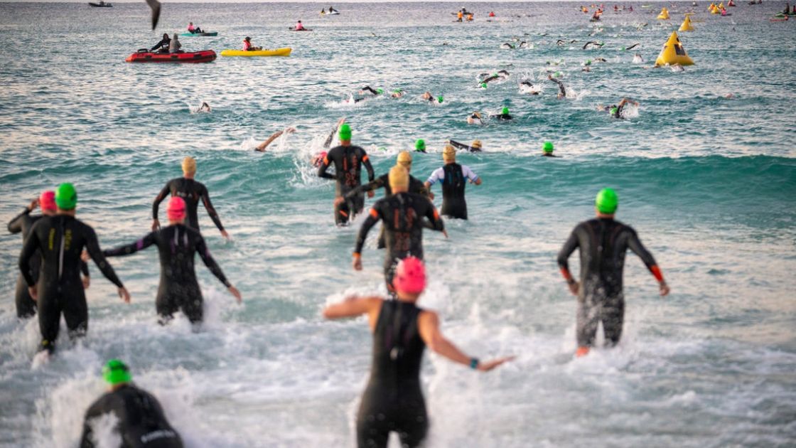 Triatletas entrando al agua en la salida de un IRONMAN bajo el reglamento IRONMAN 2026