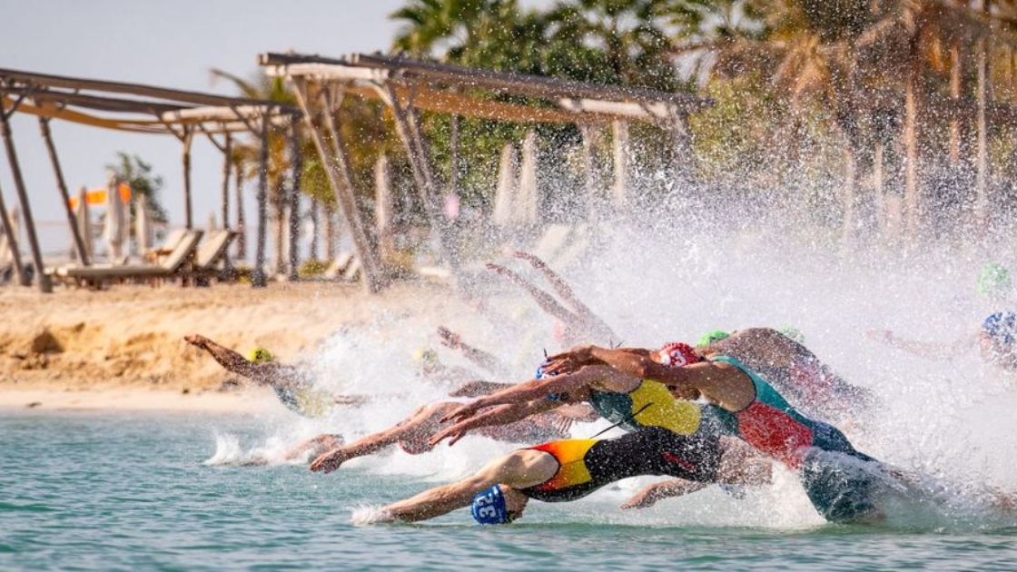 Salida masculina de la WTCS con triatletas lanzándose al agua en una playa