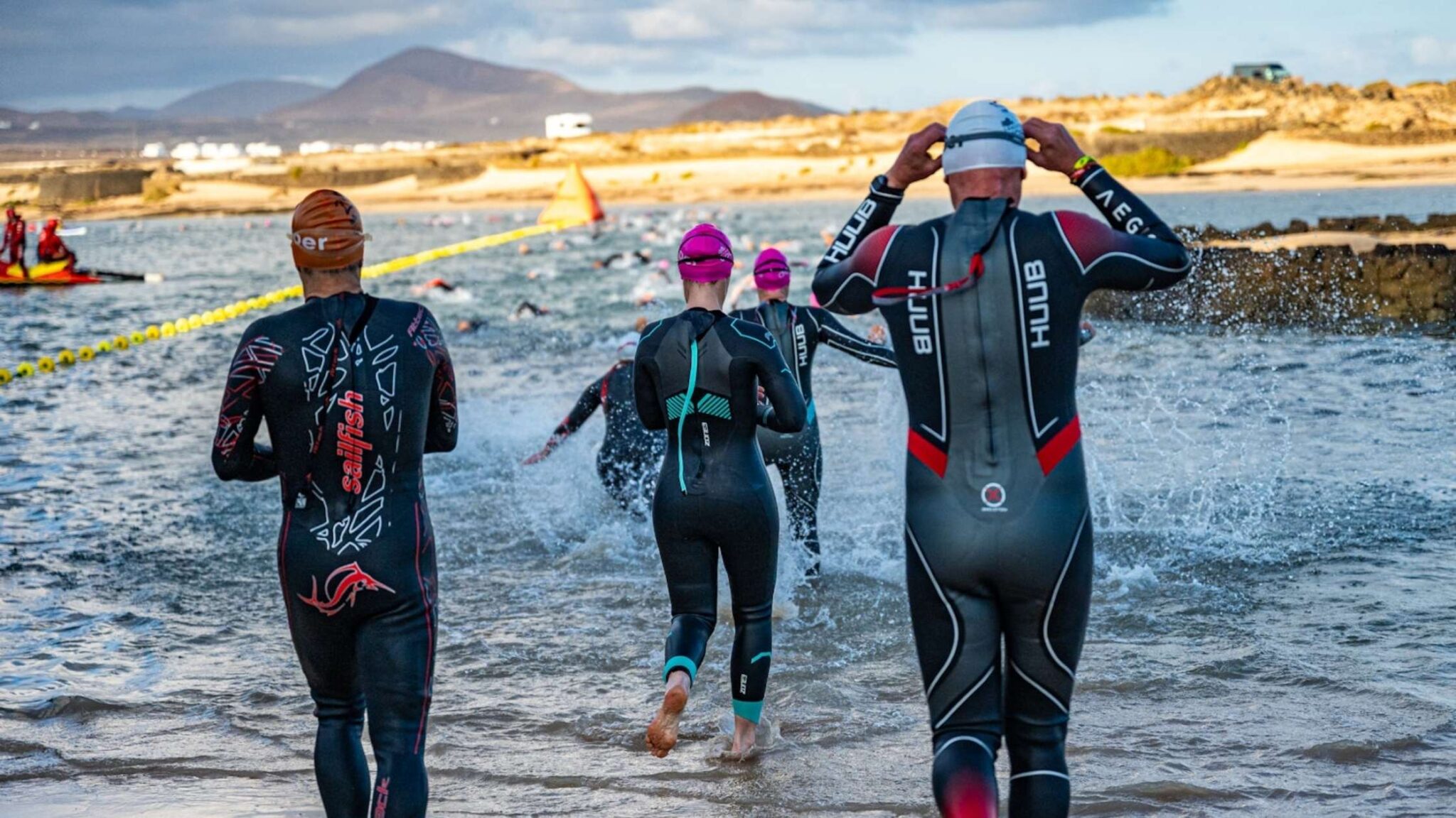 Triatletas entrando al agua en la salida del Club La Santa Volcano Triathlon en Lanzarote