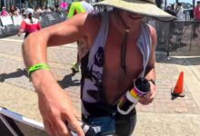 Triatleta en el IRONMAN 70.3 Oceanside 2026 entregando geles del avituallamiento fuera del recorrido
