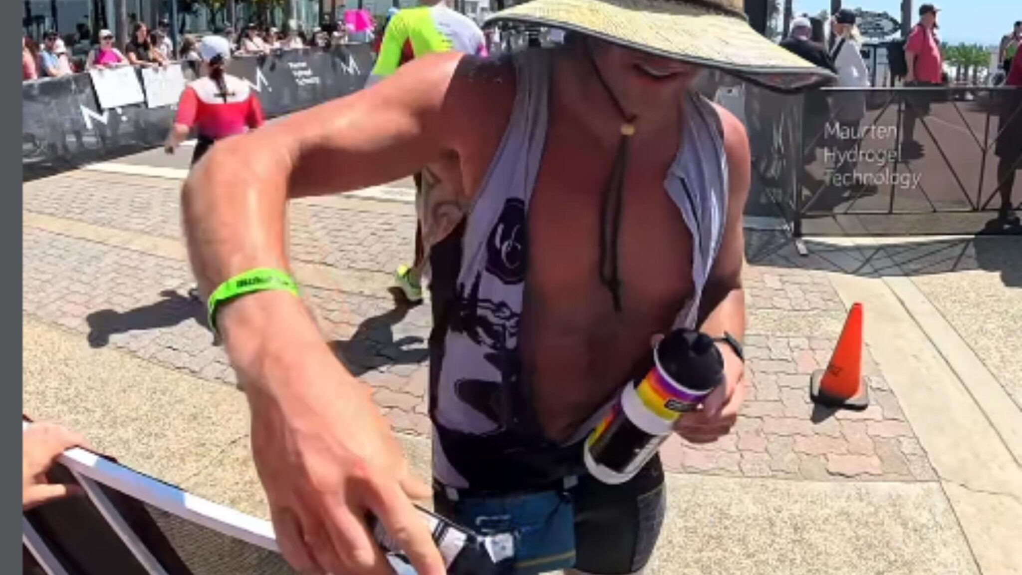 Triatleta en el IRONMAN 70.3 Oceanside 2026 entregando geles del avituallamiento fuera del recorrido