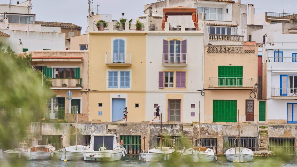Vista del Triathlon de Portocolom 2026 con triatletas corriendo junto al puerto de Mallorca