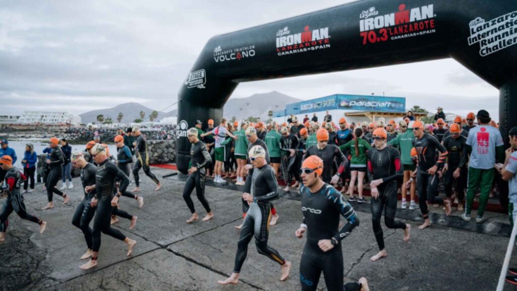 Triatletas entrando al agua bajo el arco del IRONMAN Lanzarote