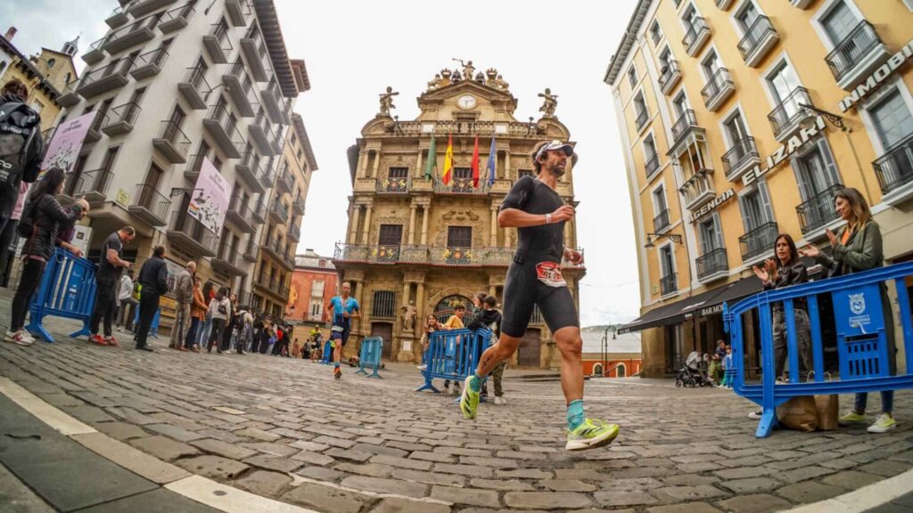 Triatletas corriendo junto al Ayuntamiento de Pamplona durante el Half Triathlon Pamplona-Iruña
