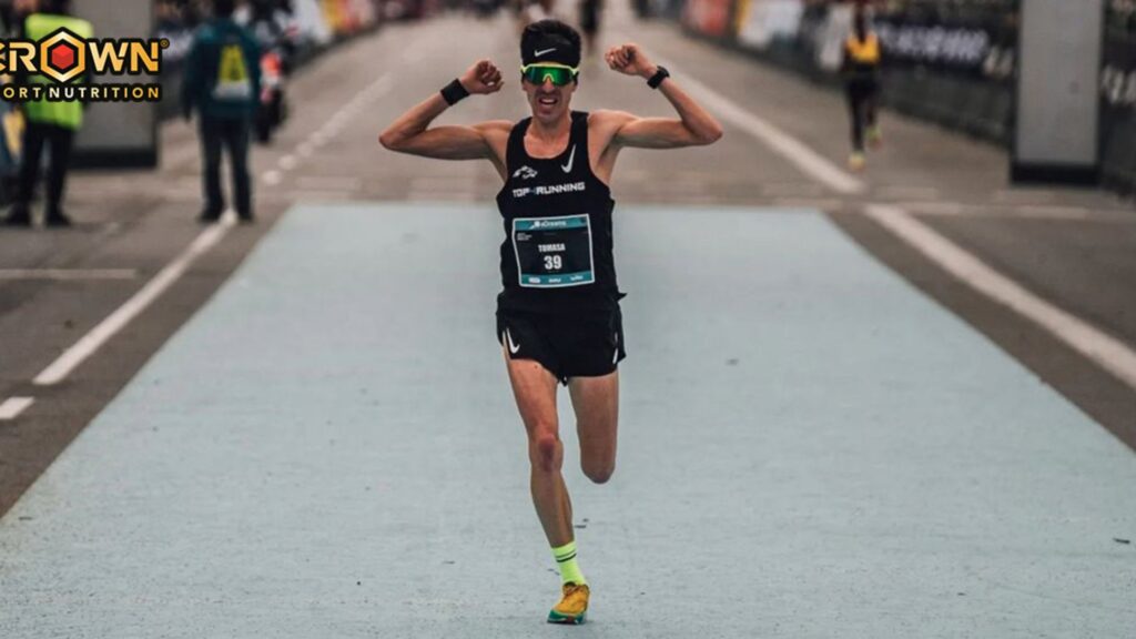 Corredor cruzando la meta en una carrera de maratón con imagen de Crown Sport Nutrition