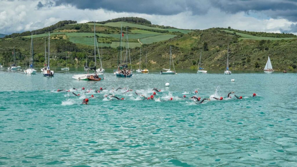 Triatletas nadando en el embalse de Alloz durante una prueba de triatlón en Navarra