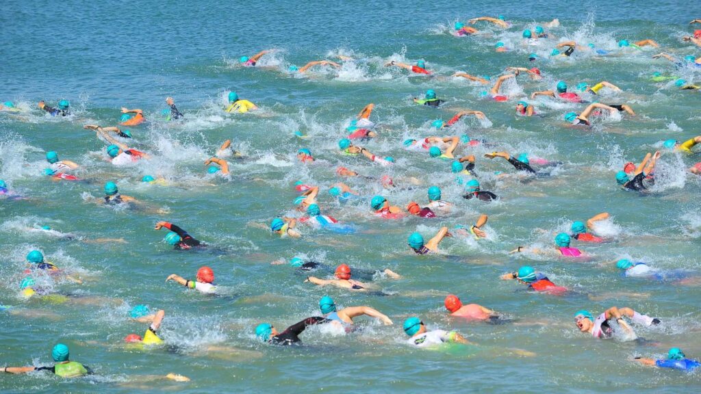Salida de natación en aguas abiertas durante un triatlón con numerosos participantes