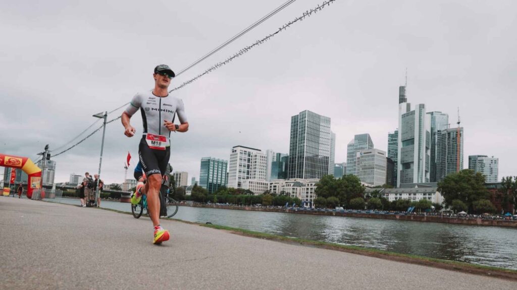 Triatleta corriendo junto al skyline de Frankfurt en el IRONMAN Frankfurt