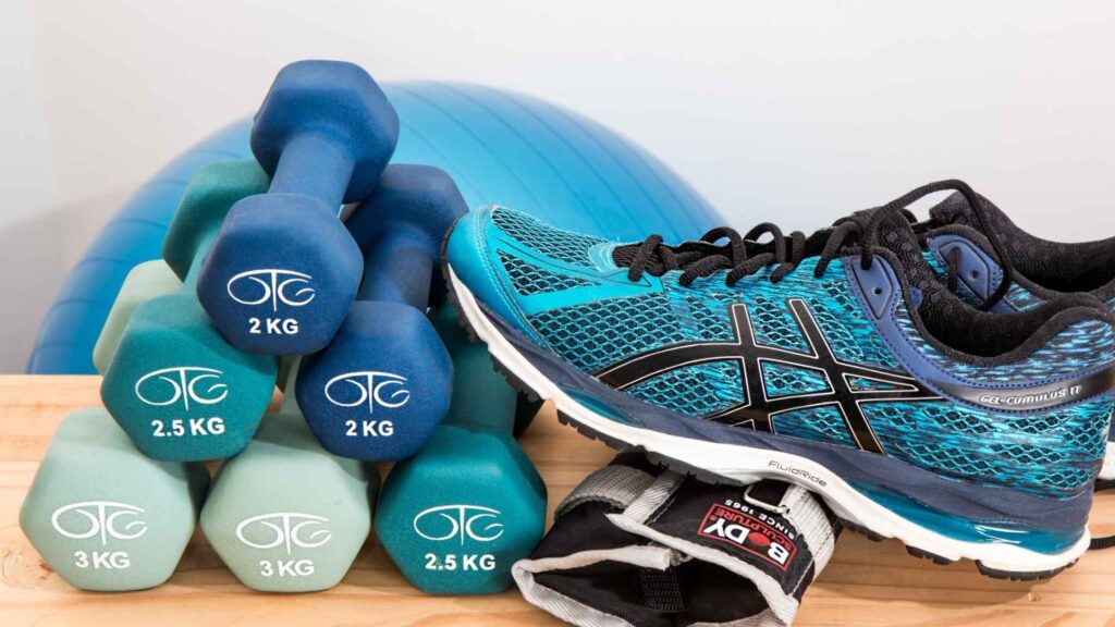 Zapatilla de running junto a mancuernas y material de entrenamiento en casa