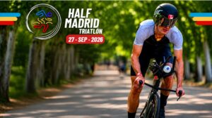 Cartel promocional del Half Madrid Triatlón 2026 con un ciclista compitiendo en carretera arbolada