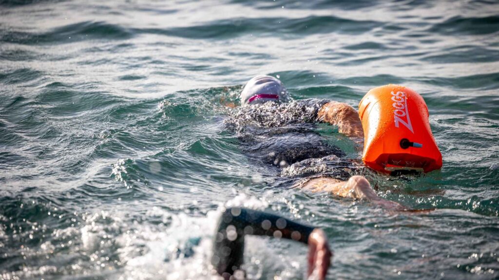Nageur s'entraînant en eau libre avec une bouée Zoggs orange