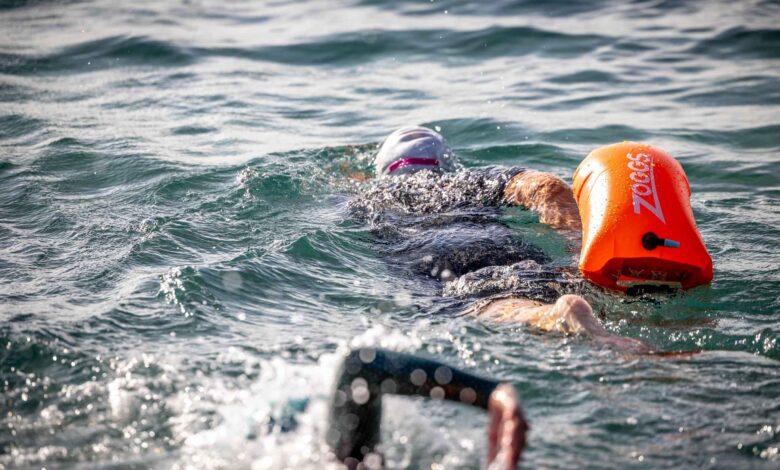 Swimmer training in open water with an orange Zoggs buoy