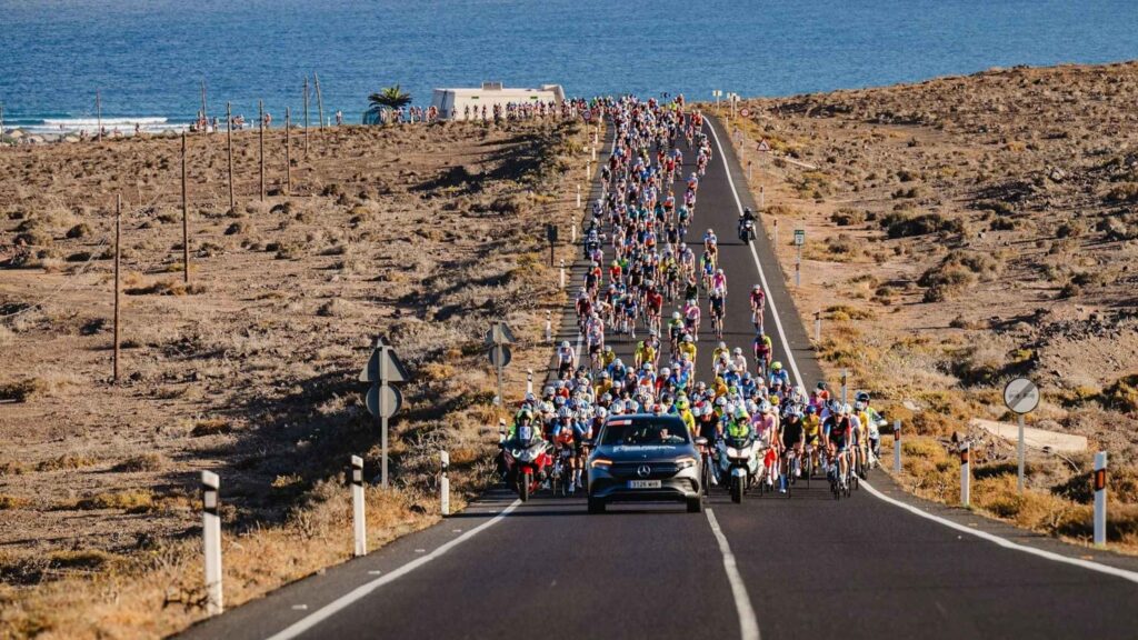 Das Peloton des Radrennens „Rundfahrt von Lanzarote“ fährt auf einer Straße am Meer entlang.