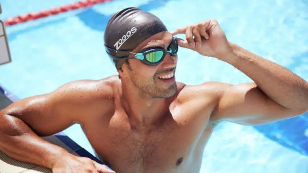 Schwimmer mit Badekappe und verspiegelter Zoggs-Schwimmbrille neben einem Freibad