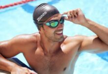 Nadador con gorro y gafas de natación Zoggs con lente de espejo junto a una piscina exterior
