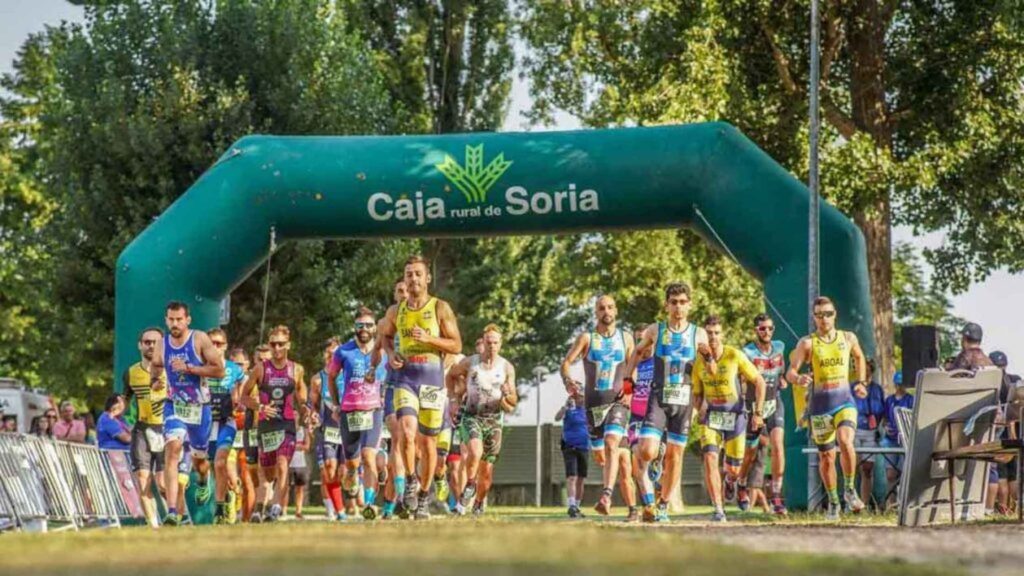 Salida de corredores en el Triatlón de Almazán bajo el arco de Caja Rural de Soria