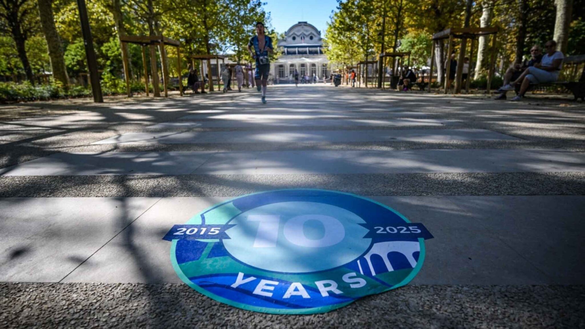 Triatleta corriendo por Vichy junto al distintivo de los 10 años del IRONMAN Vichy