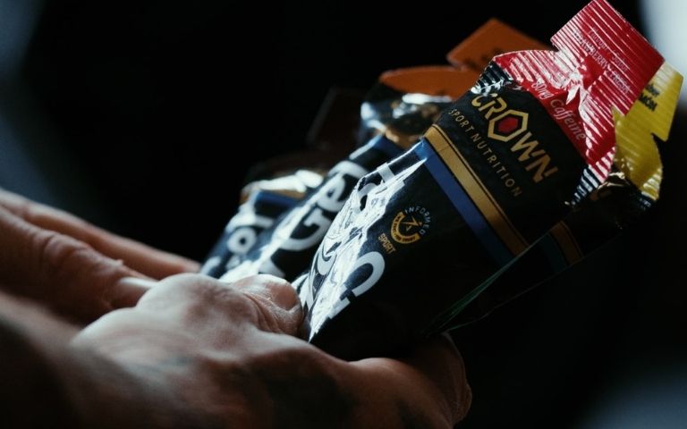 Deportista sosteniendo productos de Crown Sport Nutrition para aportar carbohidratos durante el ejercicio