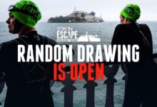 Dos participantes del Escape From Alcatraz junto a la bahía de San Francisco con la isla de Alcatraz al fondo y el anuncio del sorteo de dorsales 2027