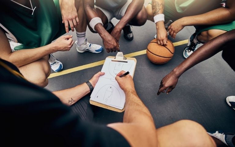 Entrenador explica una jugada a un equipo de baloncesto durante una charla táctica