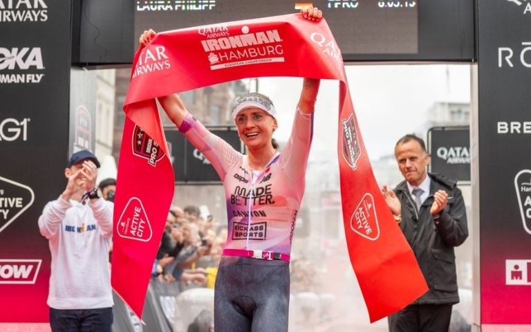 Laura Philipp celebra en la meta del IRONMAN Hamburg levantando la cinta de llegada