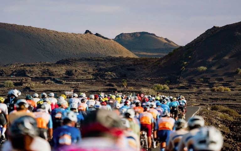 Pelotón de ciclistas durante la Vuelta Ciclista a Lanzarote entre el paisaje volcánico de la isla