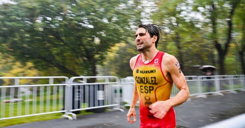 Alberto González García corriendo bajo la lluvia con el uniforme de España durante un triatlón