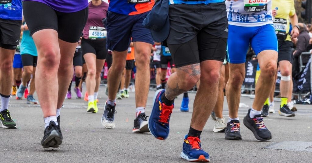 Piernas y zapatillas de varios corredores durante una carrera sobre asfalto