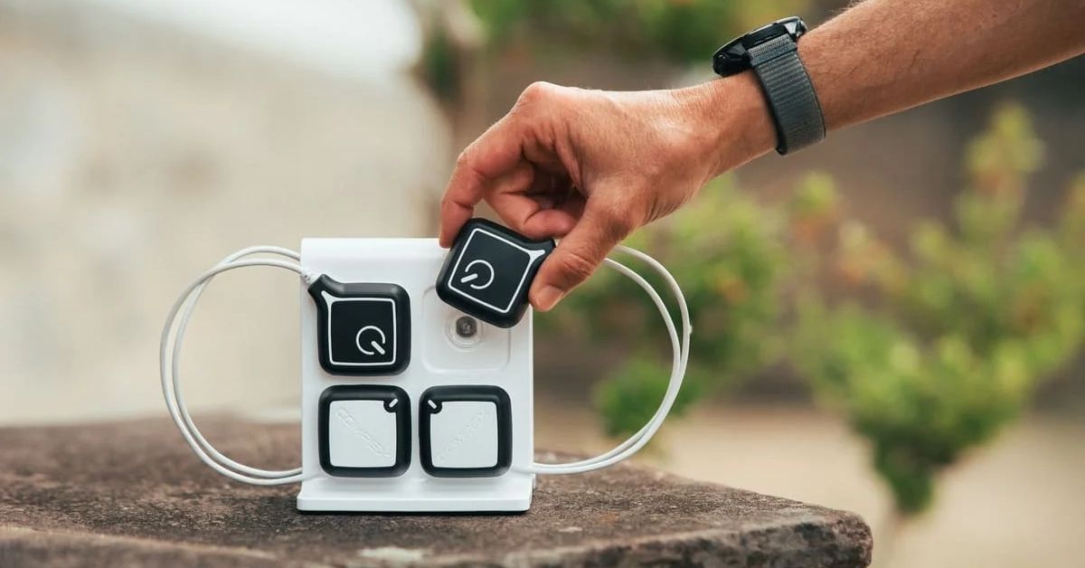 Mano colocando un módulo inalámbrico de Compex Ultimate en su estación de carga, junto a otros módulos de electroestimulación.