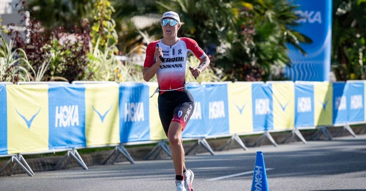 Julie Derron corriendo en el Mundial IRONMAN 70.3 de Niza 2026, con equipación roja y blanca y gafas deportivas