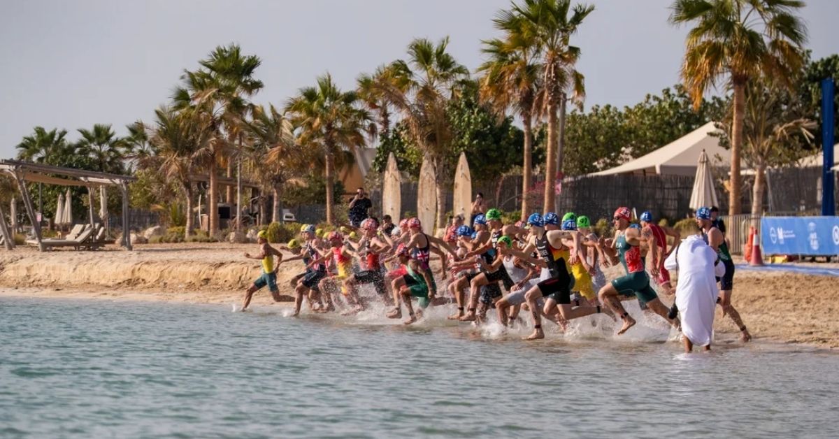 Grupo de triatletas entrando al agua en la salida de natación de una prueba en Abu Dabi